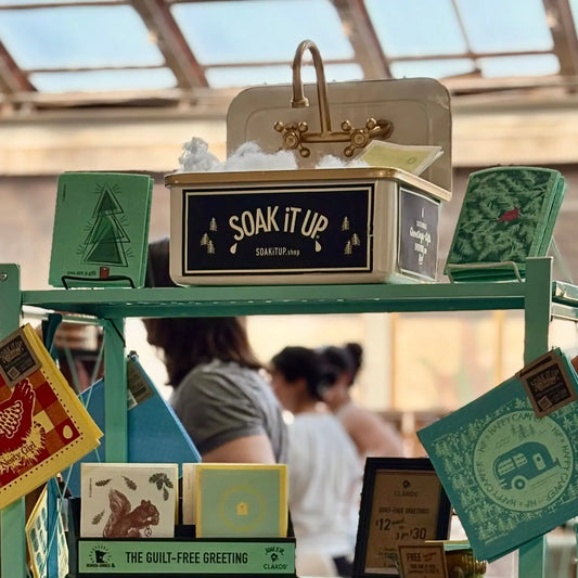 Cream-colored metal box with gold faucet handle and soak it up label featured at white bear lake holiday markets 2026