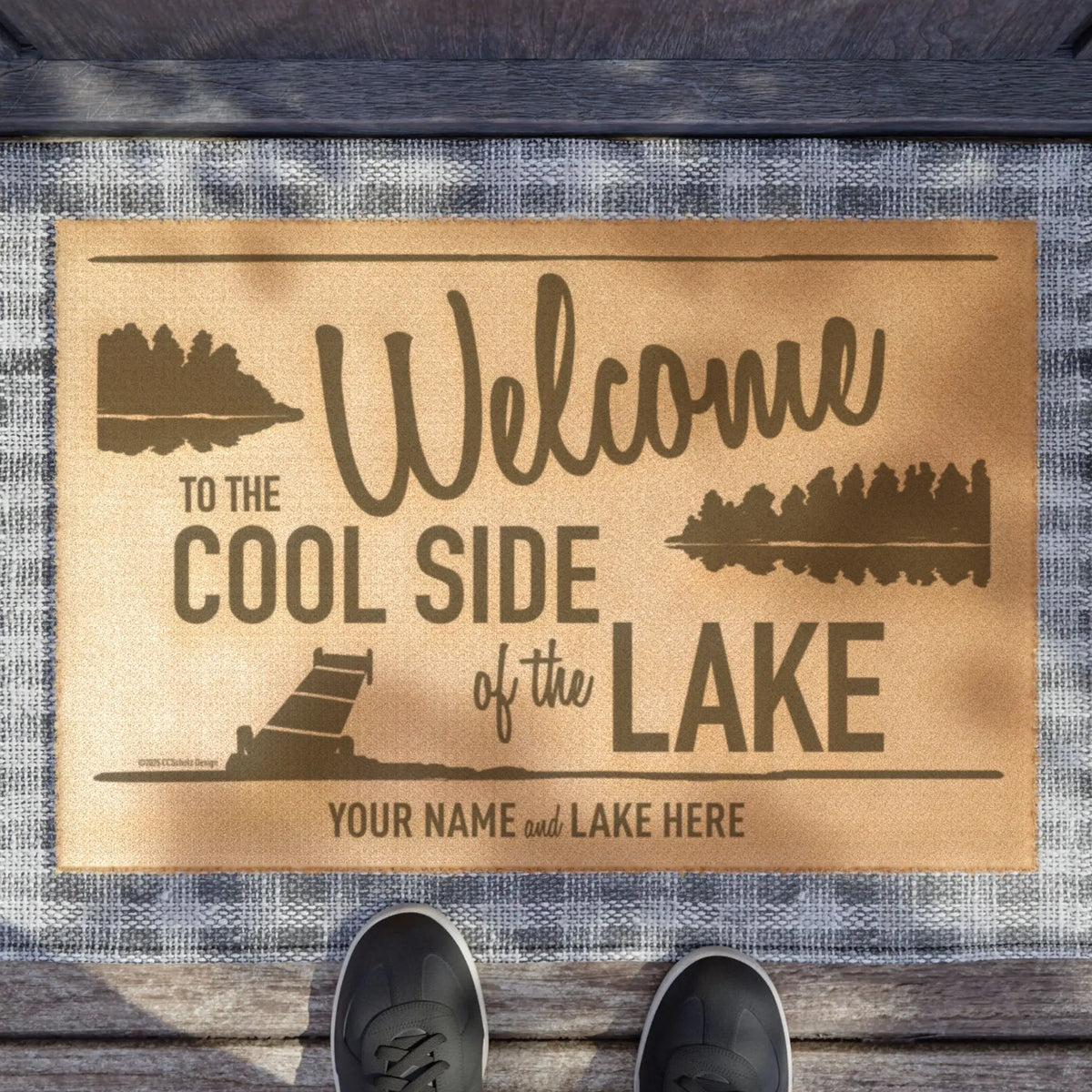 A tan welcome mat with dark brown forest silhouettes and customizable white bear lake name placeholder